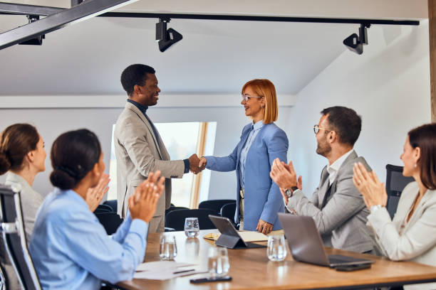 istock Two clients shaking hands after the meeting, and other people clapping hands. 2078356119