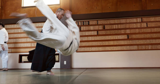 istock Japanese students, throw or sensei in dojo to start practice lesson, discipline or teaching self defense. Black belt master, people learning combat or athletes in fighting class, training or aikidoka 2078356212