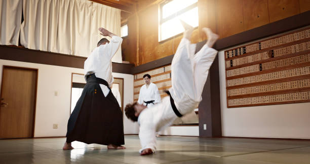 People, dojo and sensei with student in self defense or training for fight or challenge with master. Man, teacher and martial arts class in Japan for practice lesson, aikido or team battle in Tokyo