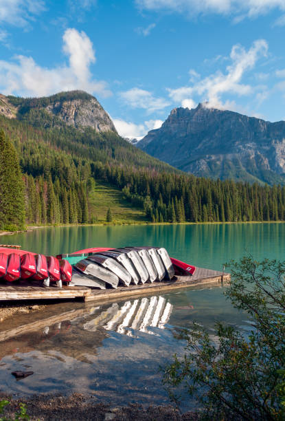 Green lake with boats, trees, mountains and sky.
