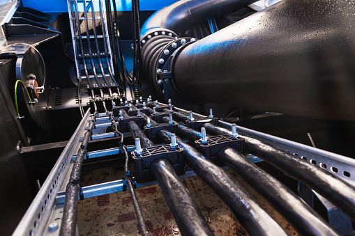 The water supply system inside the ship with a large diameter pipe and a line of high power electrical cables, close-up.