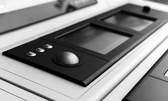 Built-in tabletop input device with trackball mouse and digital touch screens. Black and white photo with selective focus