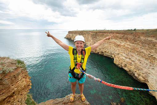 Young woman jump from the cliff with a rope. Ropejumping
