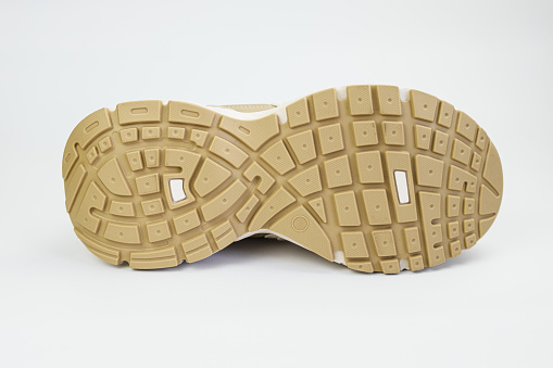 Yellow sole of sports shoes with embossed tread on a white background. Off-season shoes for sports, recreation, travel.