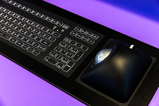 Built-in tabletop industrial input device with black keyboard and trackball mouse. Modern electronic navigation equipment mounted at the captains bridge