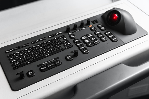 Built-in tabletop input device, black industrial keyboard with a trackball mouse, modern navigation equipment mounted on a control panel at captains bridge. Marine navigation simulation system