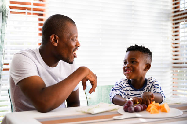 istock Cute boy with mouth full of grapes sharing fruit with father 2078379841