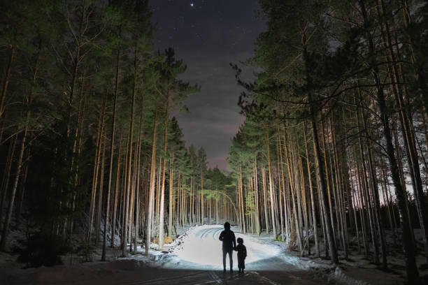 istock Night scene, a child with a parent with a flashlight in a dark forest in winter. 2078381021
