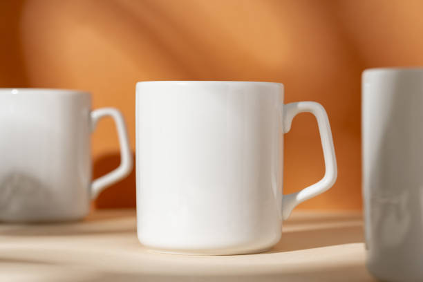 istock White ceramic mugs on peach background with shadows 2078430393