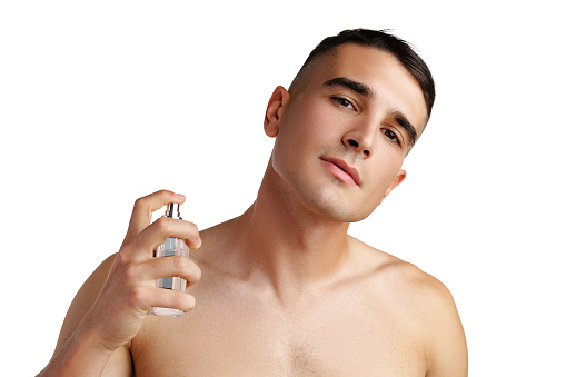 Handsome young man applying perfume on white background close up