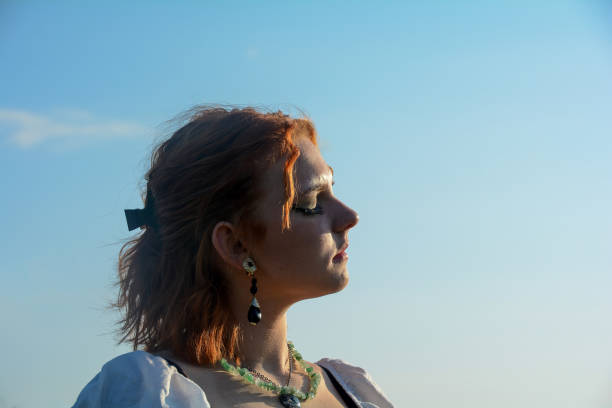Profile of a pretty young woman, face to the sun, with sky