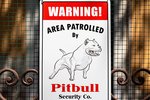 Venice, Veneto - Italy - 06-09-2021: Sign warning that the area is patrolled by 'Pitbull Security Co.' against a mesh fence