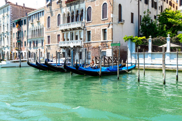 Venice, Veneto - Italy - 06-10-2021: Moored gondolas line the waterway beside historic Venetian buildings under a clear sky