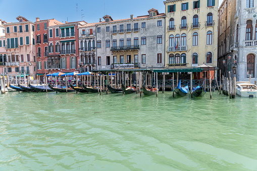 Venice, Veneto - Italy - 06-10-2021: Gondolas docked by vibrant Venetian buildings on a sunny day