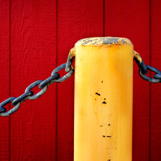 Heavy chain and yellow pole for safety and security with red wall in the background