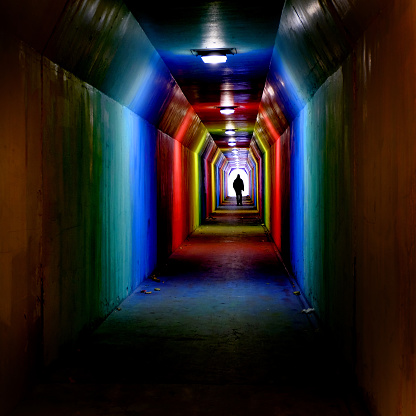 Person silhouetted silhouette walking through colorful tunnel towards achievement