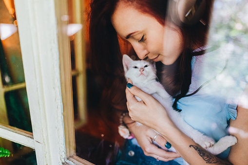 Young woman with cat staring through the window