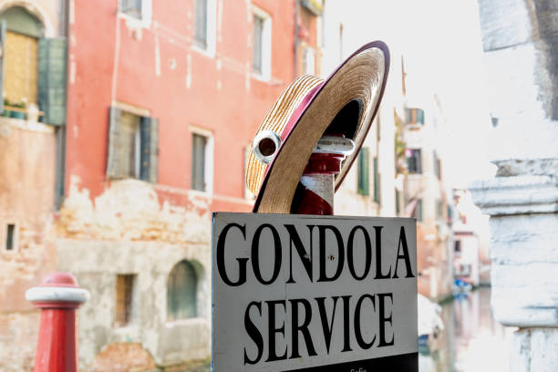 Venice, Veneto - Italy - 06-10-2021: Gondola service sign and traditional straw hat by a Venetian canal with colorful backdrop