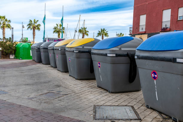 Puerto de Mazarron, Murcia - Spain - 01-18-2024: Row of multicolored recycling bins for waste separation on a Spanish promenade