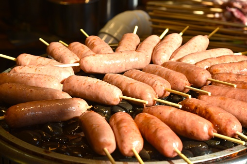 grilled sausage meat stabbing in wooden stick on gridiron street food in Chinaclose up of