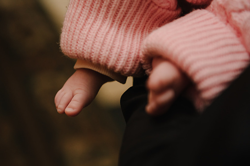 Small bare feet of a girl. Barefoot. A mother holds a baby in her arms. Tiny, feet of newborn infant closeup. Cute sleeping daughter at baptism ceremony in church.
