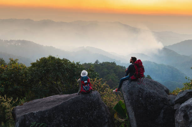 istock man and a woman are sitting on a rock overlooking a mountain range 2078490636