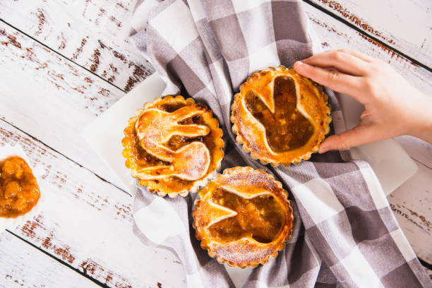 istock Kids hand taking a tartlets sprinkled with powdered sugar with peach jam 2078499247