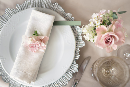 Delicate wedding table setting. A plate with a napkin and a rose.