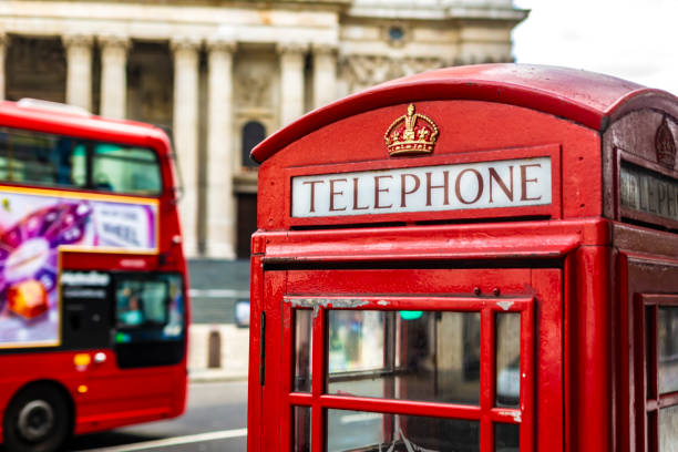 Low angle view of traditional old style UK red telephone box isolated against a building background