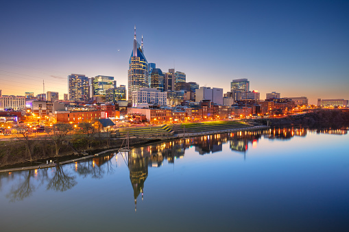 Cityscape image of Nashville, Tennessee, USA downtown skyline with reflection of the city the Cumberland River at spring sunset.