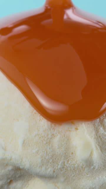 Table top view of Scoop of vanilla ice cream covered with caramel on blue background