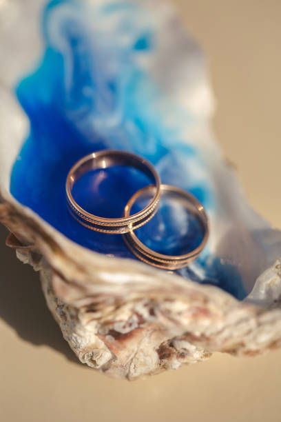 Close-up view of wedding rings in a shell on a table with wedding decor at a wedding ceremony on the beach,
