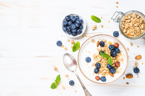 Yogurt granola with blueberries on white wooden table. Top view with copy space.