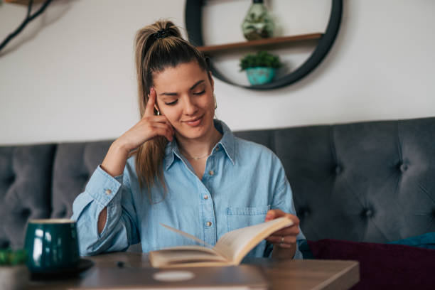 istock Young female reading book at cafe. 2078559763