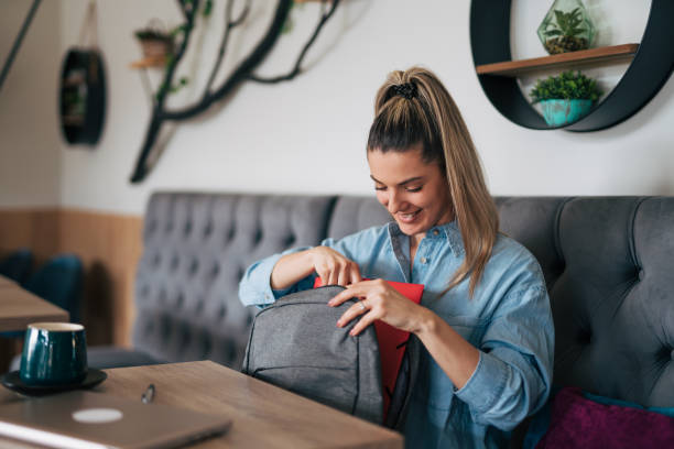 istock Young female packing her backpack at cafe 2078560822