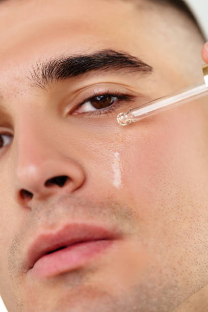 istock Handsome man applying skincare serum at camera close up 2078564511