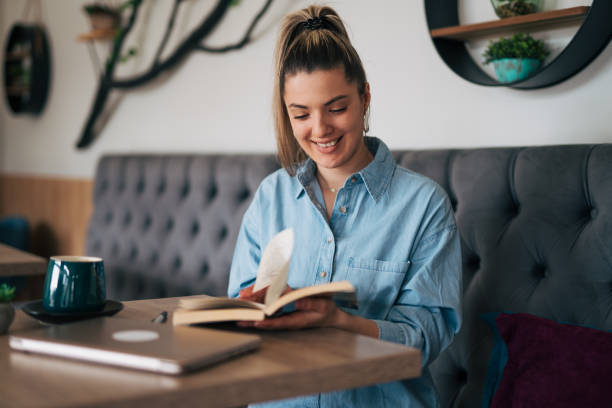 istock Young female reading book at cafe. 2078565026