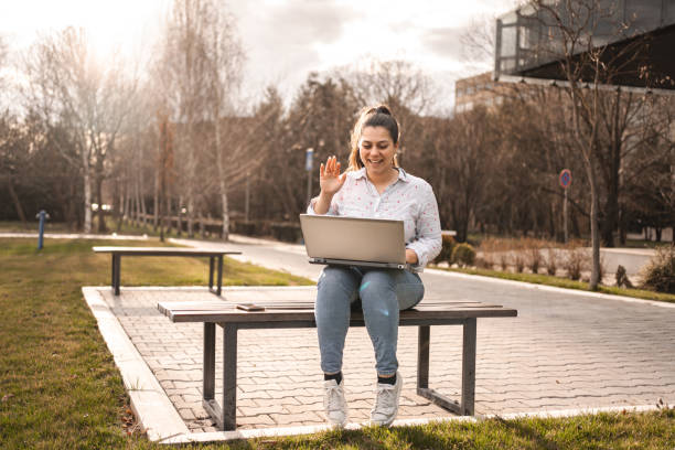 istock Woman outdoors talking on a phone call while using laptop in public park 2078567656