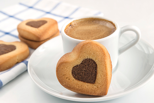 White cup of coffee and cookies shaped heart on white background