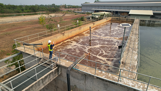 Drone view of Environmental Specialist walking through and  work inspecting water treatment pond