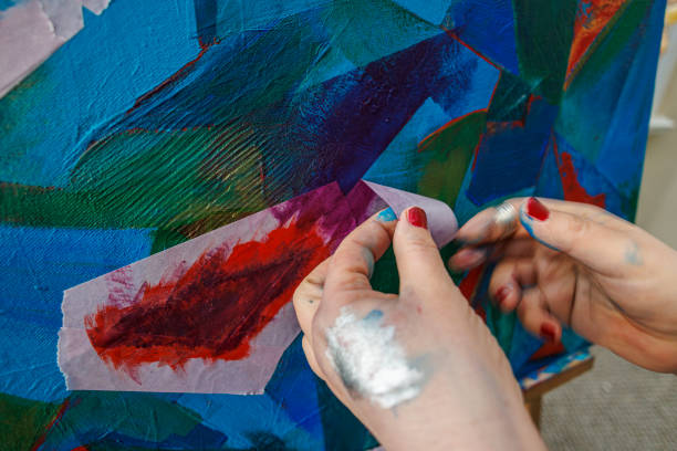istock Masking tape removal from the art canvas. A woman, a painter, is using painter tape when she is working on the painting in her studio 2078614189
