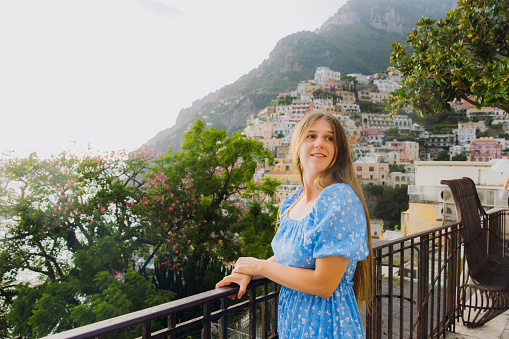 Side view of female tourist with long hair exploring Positano town of Amalfi Coast admiring a view of cliffside houses during summer sunset