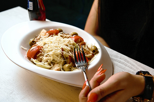 A person holds a fork and a bowl of food.