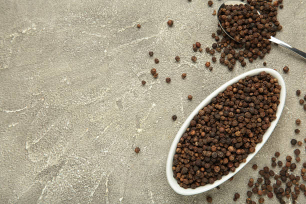 istock Black peppercorns in plate and spoon on grey concrete background. 2078633991