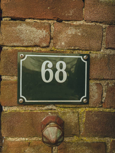 A metal plate with the number 68 on a brick wall