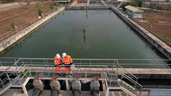 Aerial view shot of two diverse environmentalists Working on the sunlight at a wastewater treatment plant in the industrial estate by walking around and checking the quality of the water