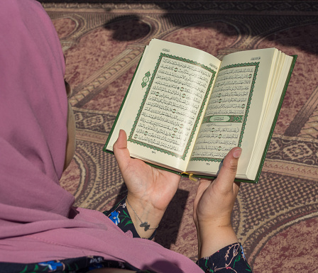 Top view of women's hands holding the holy Quran in Mosque
