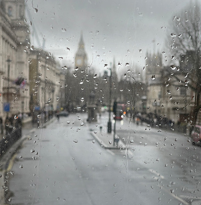 Impressionistic view of Westminster from a London double-decker bus in the rain. Point of focus are foreground raindrops on the bus window.