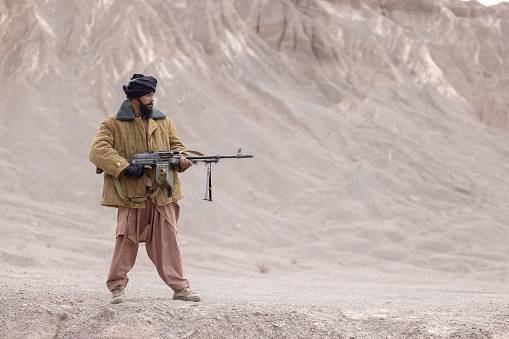Fighter with machine gun on a desert mountain
