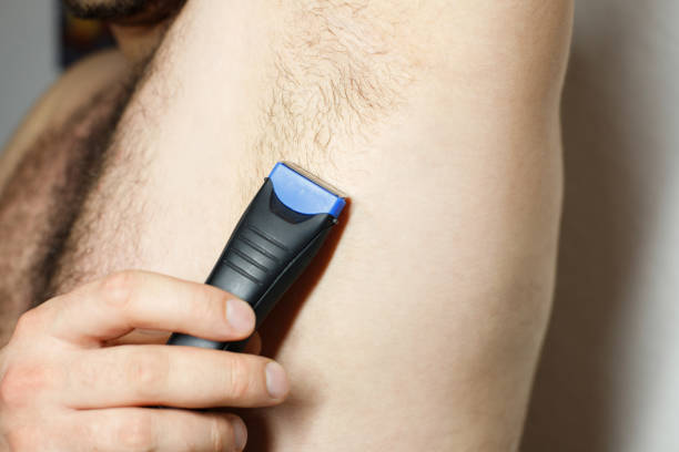 istock Male depilation. man using trimmer to remove hair from his armpit 2078756144
